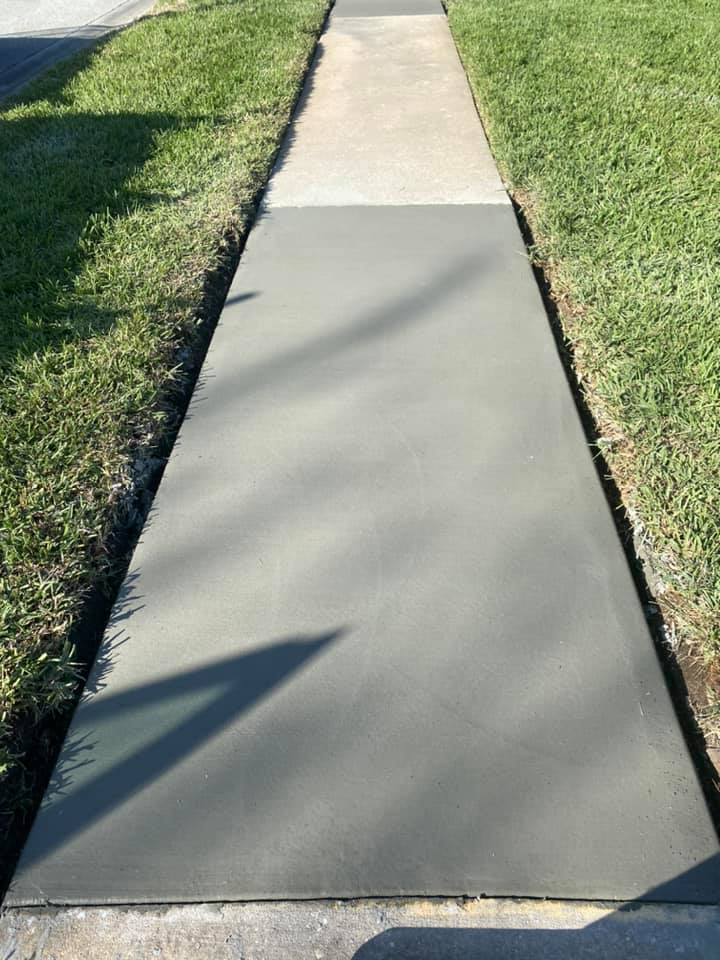 Newly poured gray concrete sidewalk next to a green lawn.