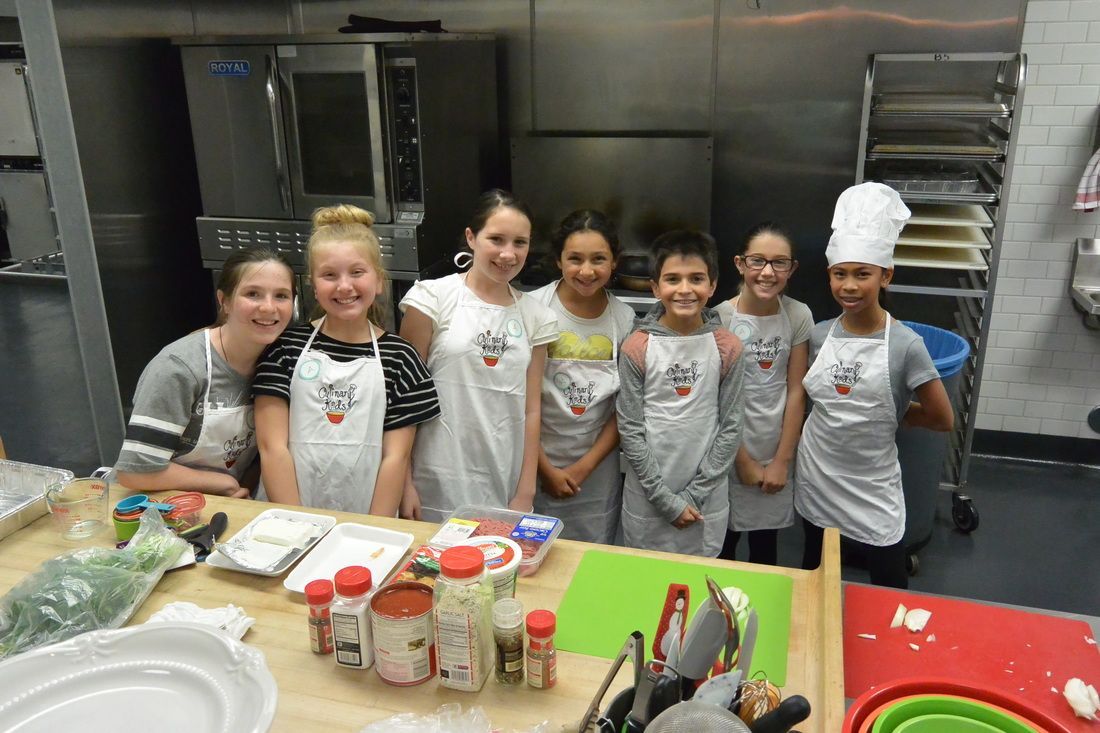 A group of young girls are posing for a picture in a kitchen.
