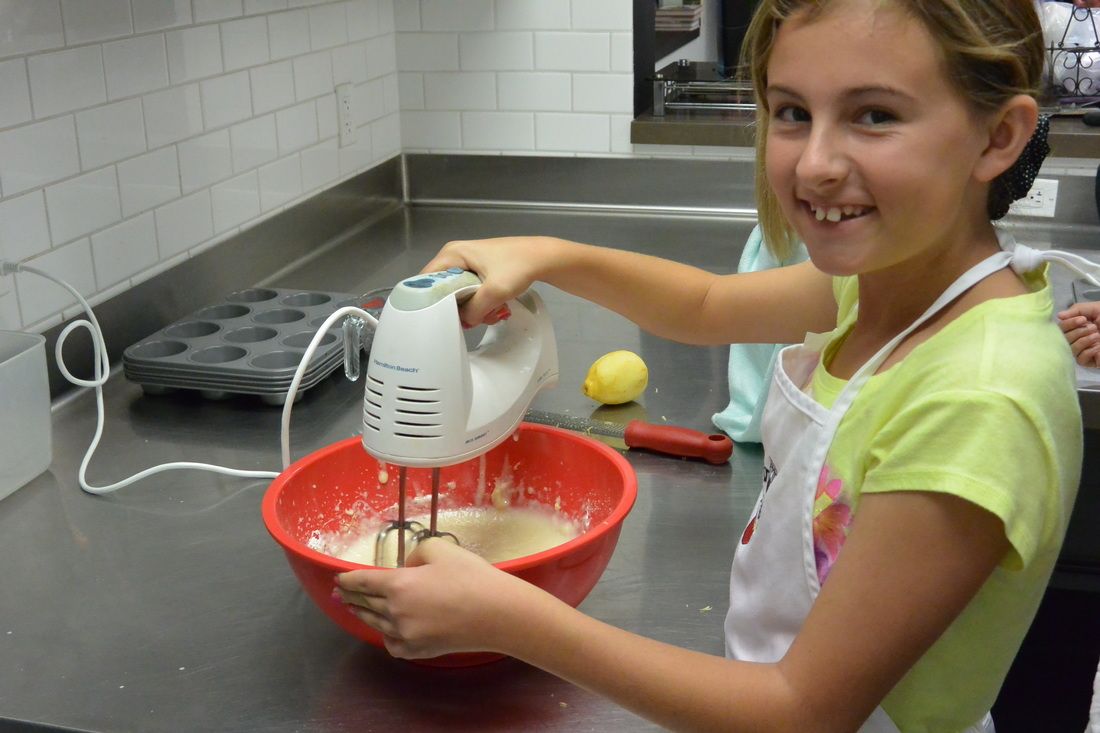 A young girl is mixing something in a bowl with a mixer