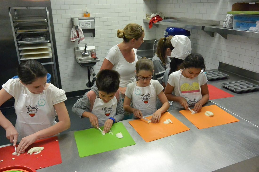 A group of children are sitting at a table in a kitchen preparing food.
