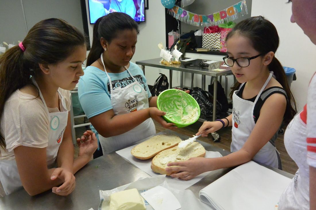 A group of young girls are preparing food at a table.