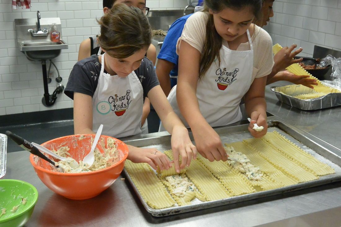 A group of young girls are preparing food in a kitchen.