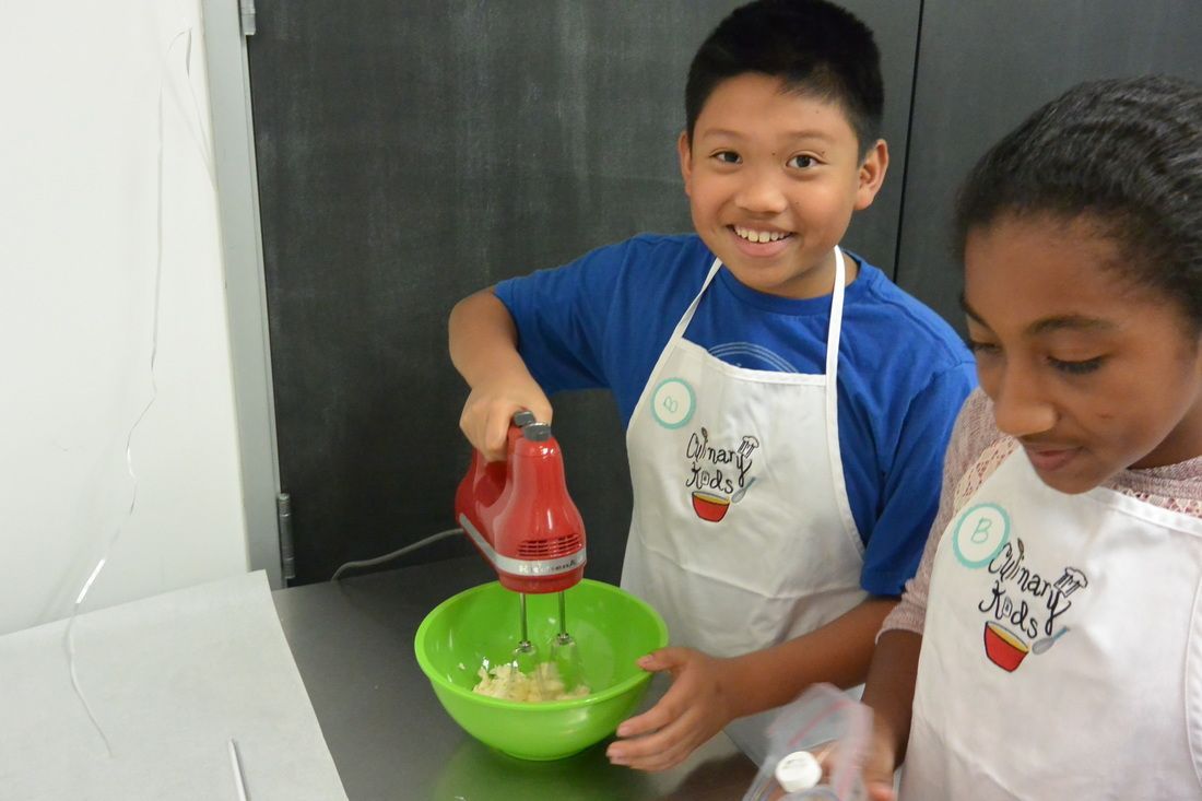 A boy and a girl are using a mixer in a kitchen