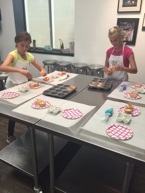 Two young girls are preparing food at a table