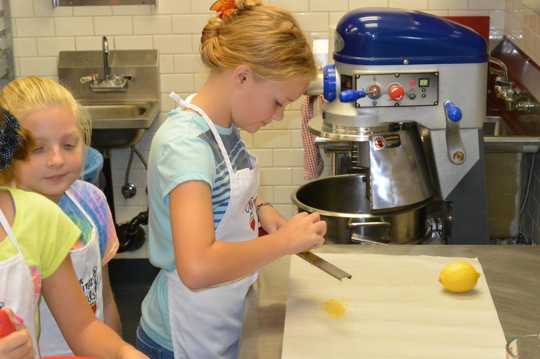 A girl is standing in front of a mixer in a kitchen