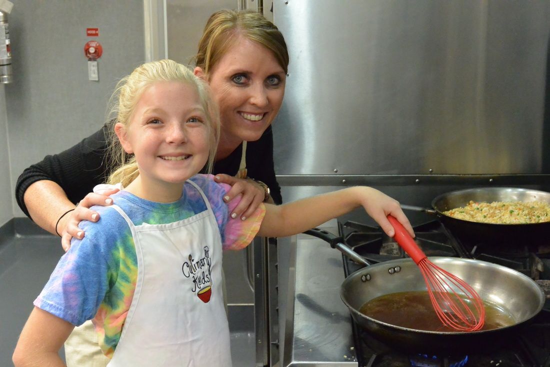A woman and a little girl are cooking in a kitchen