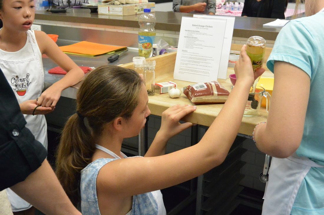 A girl is looking at a piece of paper on a table.