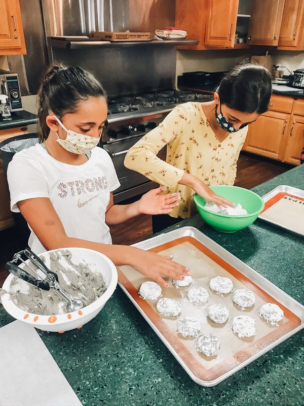 A woman and a girl are making cookies in a kitchen.