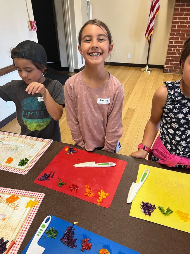 A group of children are sitting at a table making gummy bears.