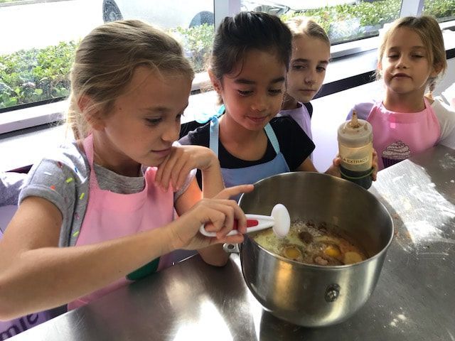 A group of young girls are mixing ingredients in a bowl.