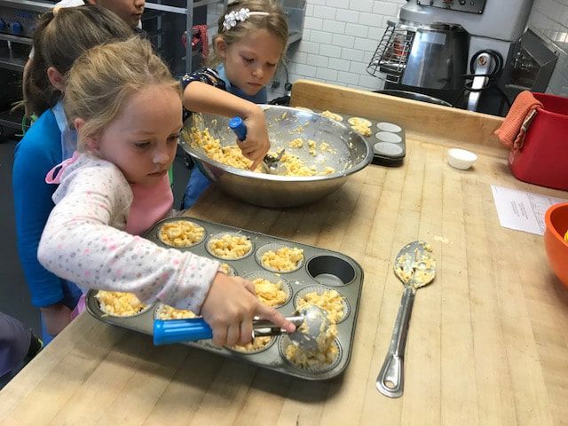 A group of young girls are preparing food in a kitchen.