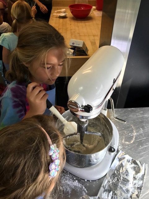 Two young girls are mixing something in a mixer.