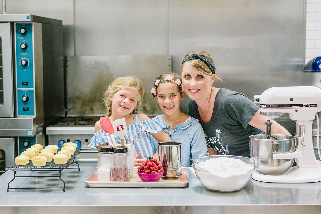 A woman and two girls are posing for a picture in a kitchen.