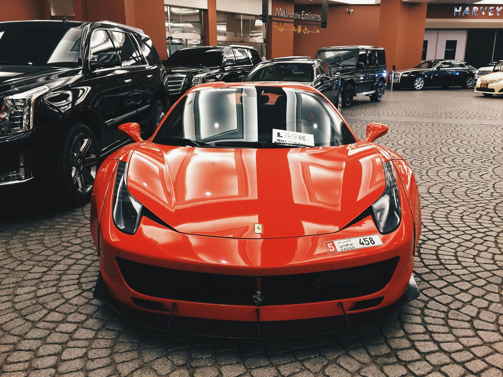 Une Ferrari rouge est garée à l'intérieur, entourée d'autres véhicules.