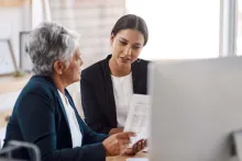 Two women reviewing papers together at a desk in an office-like setting