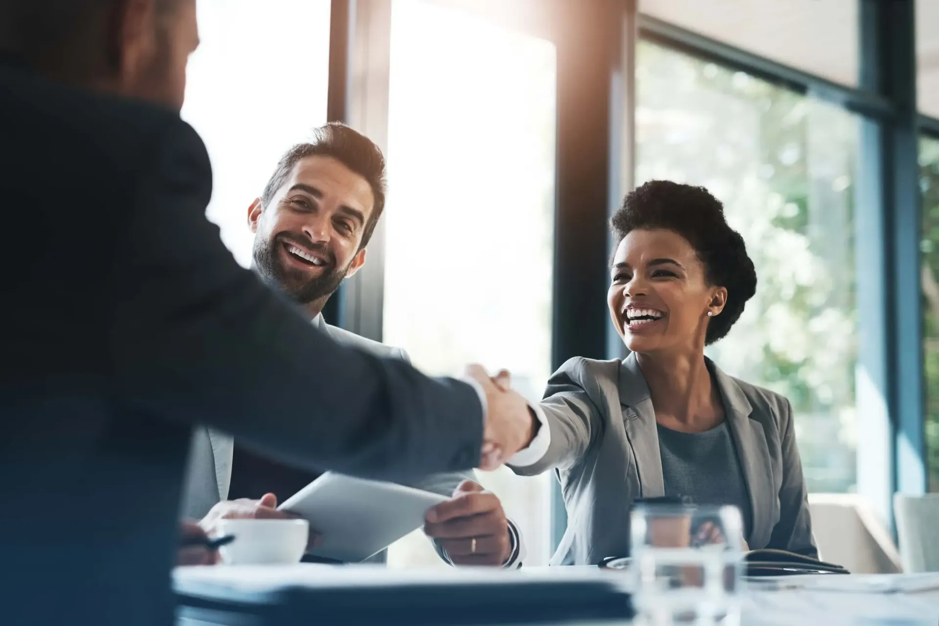 Business meeting with two people shaking hands across a conference table in a bright office