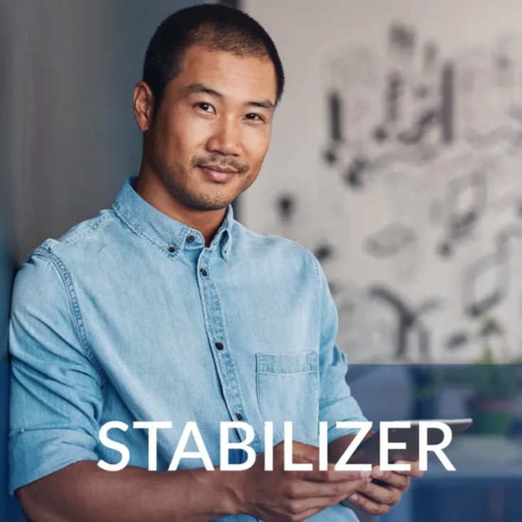 Man in a light blue shirt standing beside the word “STABILIZER” on a blurred background