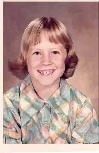 Smiling child in a pastel plaid shirt against a plain studio backdrop