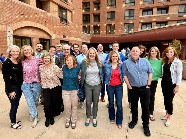 Group of people posing in front of a brick building courtyard, smiling at the camera.