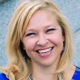 Smiling blonde woman in a blue top against a light blue background