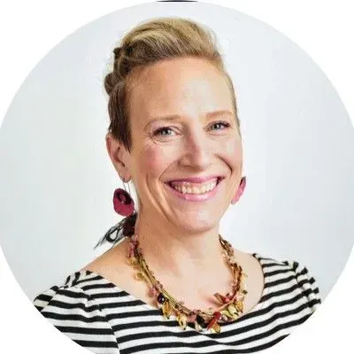 Smiling person in a striped shirt and floral necklace against a light background