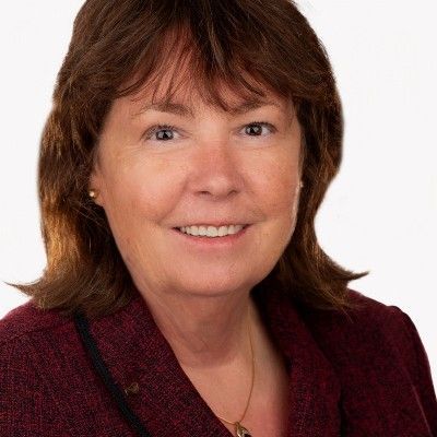 Portrait of a smiling woman in a burgundy jacket against a white background