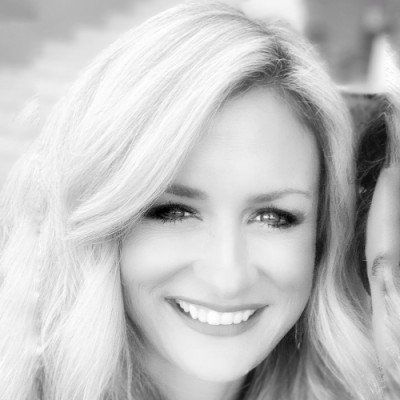 Smiling blonde woman in a black-and-white portrait, facing the camera.
