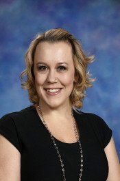 Smiling woman in a black top against a blue studio backdrop