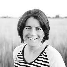 Black-and-white portrait of a smiling person in a striped shirt outdoors