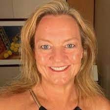 Smiling blonde woman posing indoors in a sleeveless top