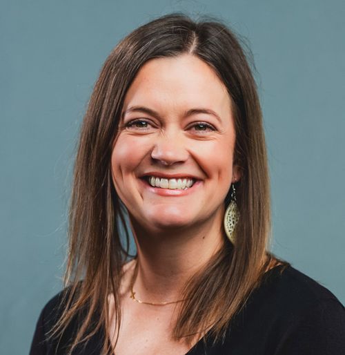 Smiling woman with long brown hair against a teal background