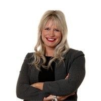 Smiling blonde woman with crossed arms wearing a dark sweater on a white background