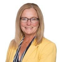 Smiling blonde professional in glasses and a yellow blazer against a white background
