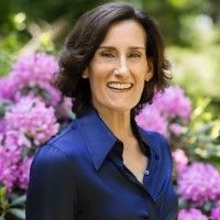 Smiling woman in a navy shirt standing in front of blooming purple flowers