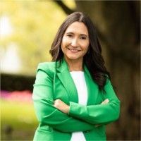Smiling woman in a bright green blazer standing outdoors with arms crossed