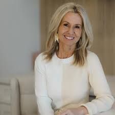 Smiling woman in a white sweater seated indoors against a neutral background