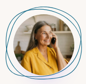 Smiling woman in a mustard blouse talking on a phone, framed by blue circular lines.