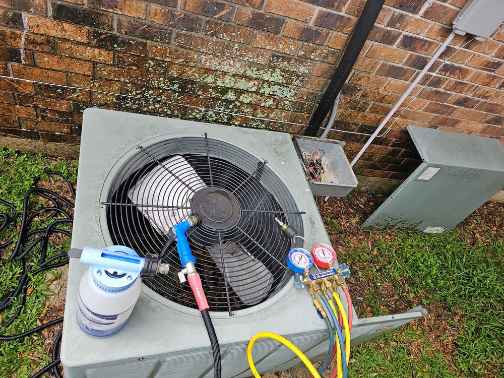 Technician in blue plaid shirt inspecting HVAC gauges with red and blue dials near a ceiling unit