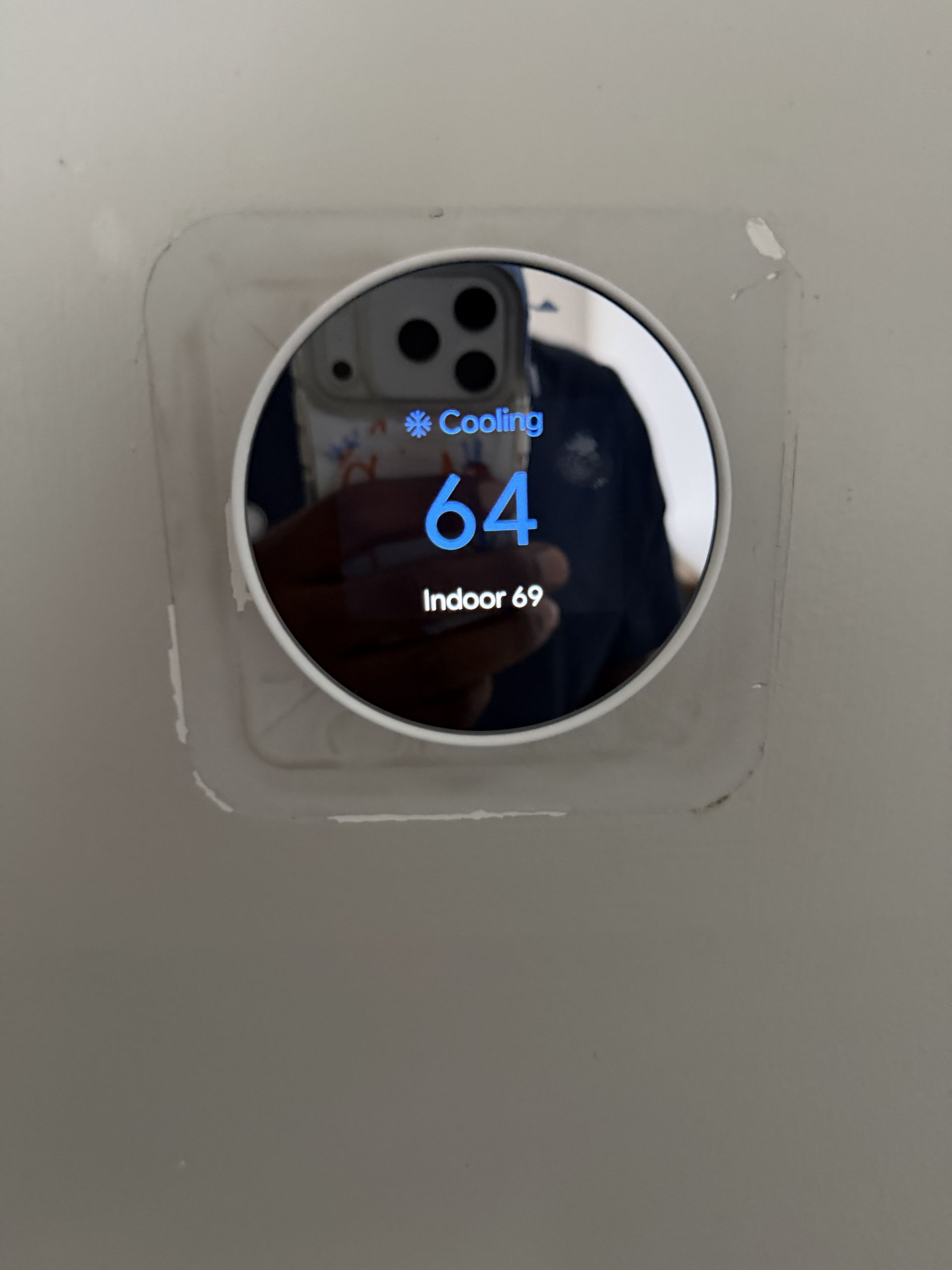 Round thermostat display showing “Cooling,” 64, and indoor temperature of 49.