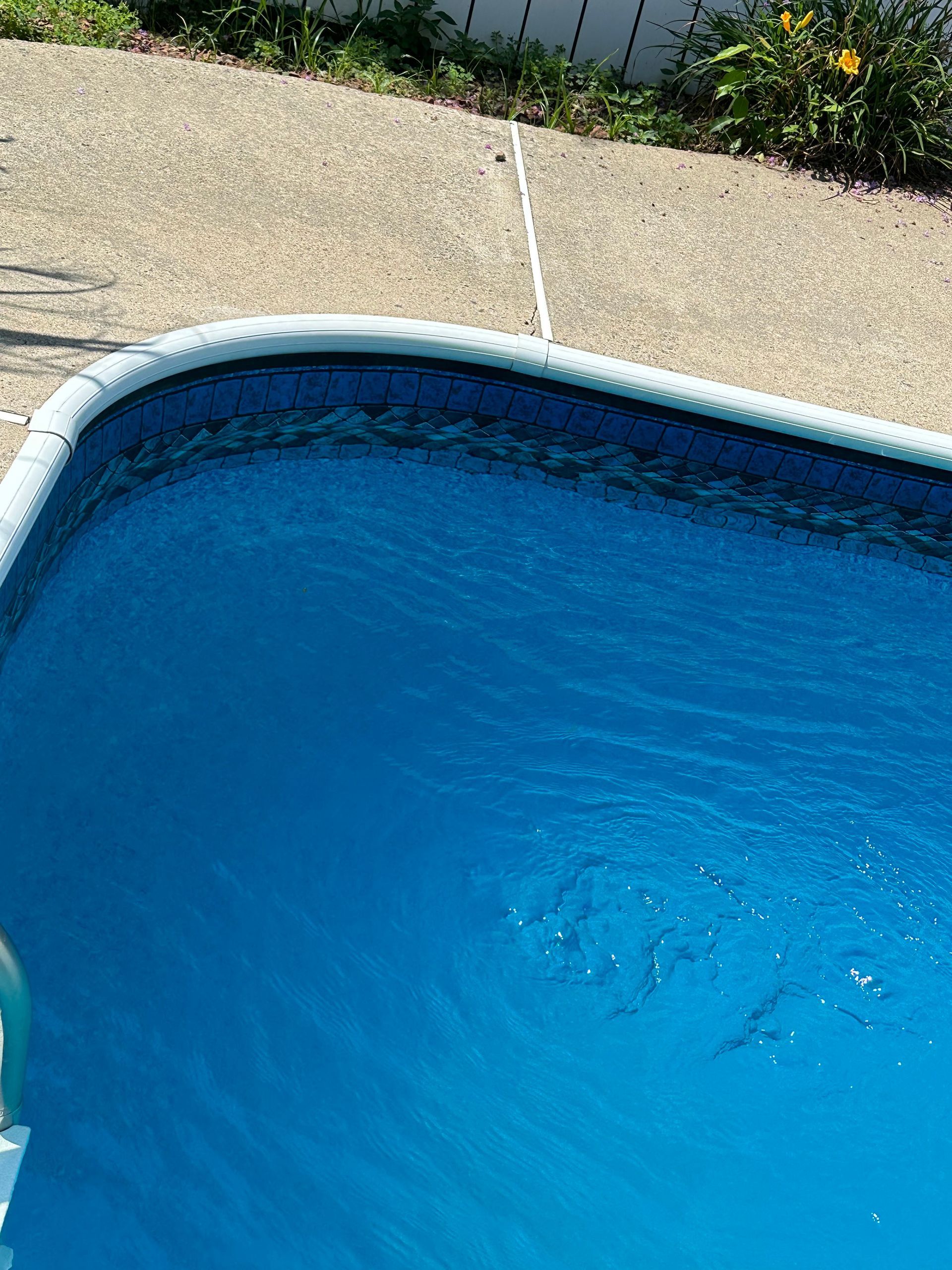 Blue swimming pool beside a gravel patio and garden border