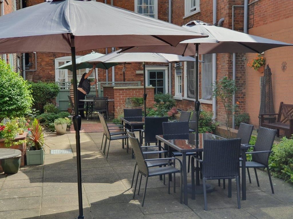 A patio with tables and chairs under umbrellas in front of a brick building.