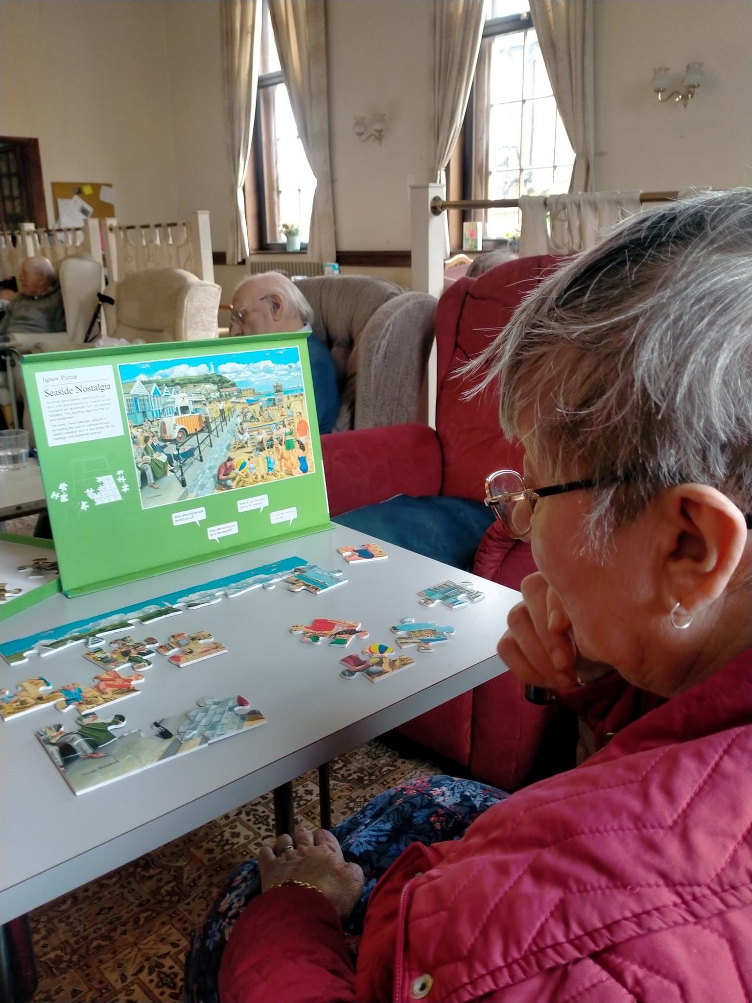 A woman is sitting at a table with a puzzle on it.