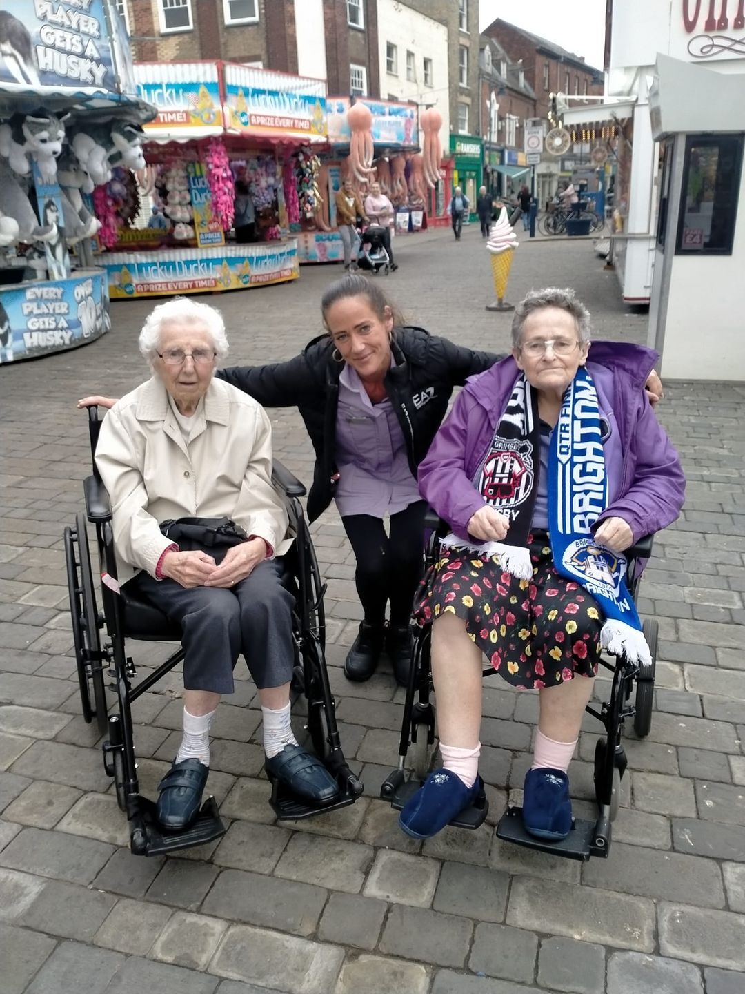 Three elderly women in wheelchairs are posing for a picture