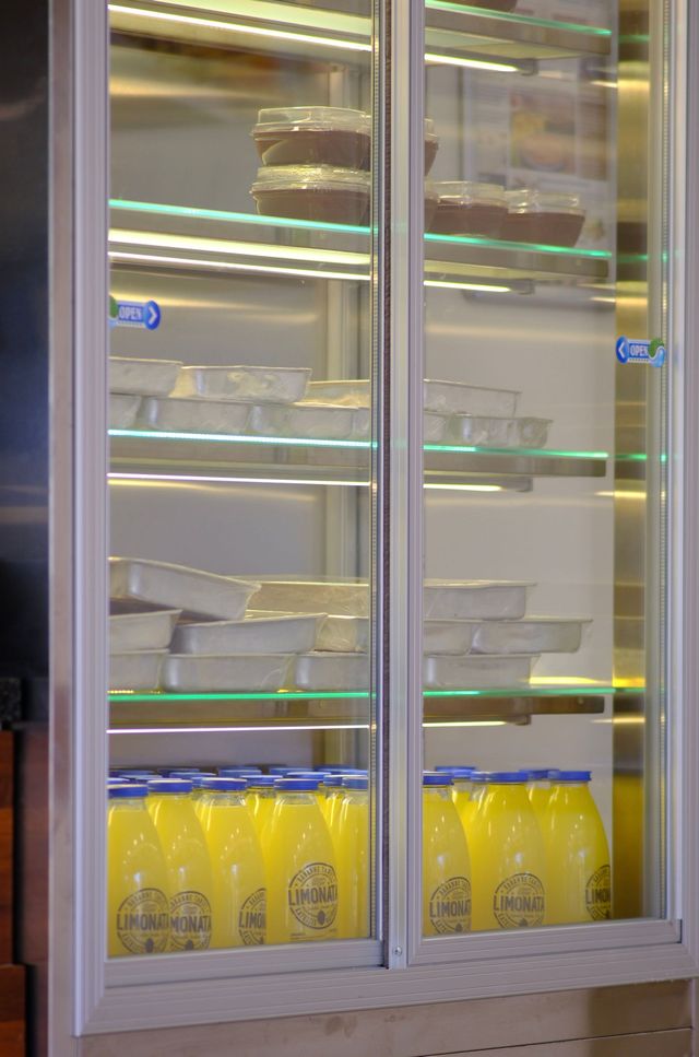 Glass-door freezer filled with rows of yellow bottles and stacked white cartons inside a store