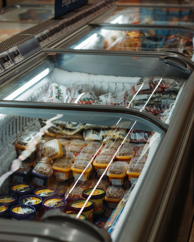 Ice cream freezer case with assorted tubs and flavors under glass lids