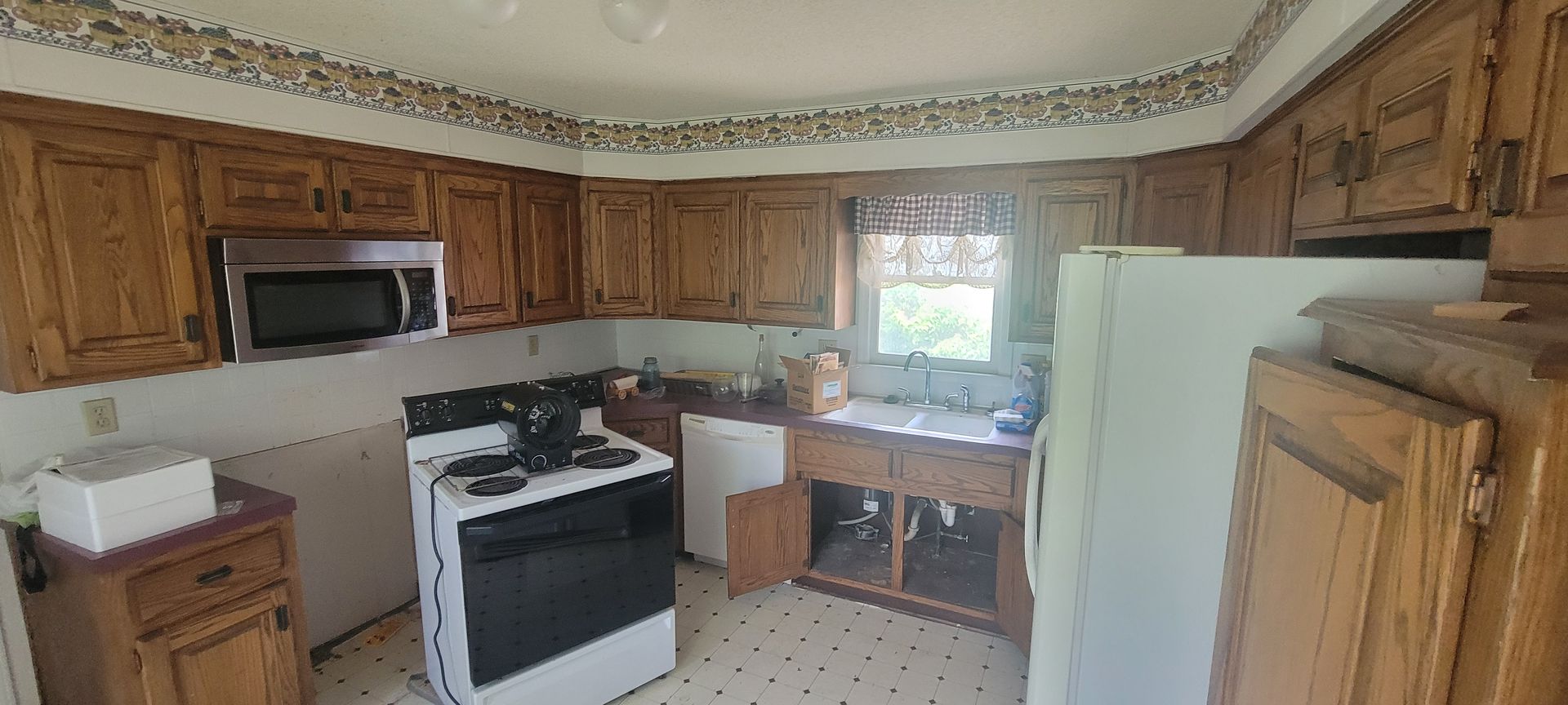 A photo of a kitchen with the appliances pulled out away from the wall