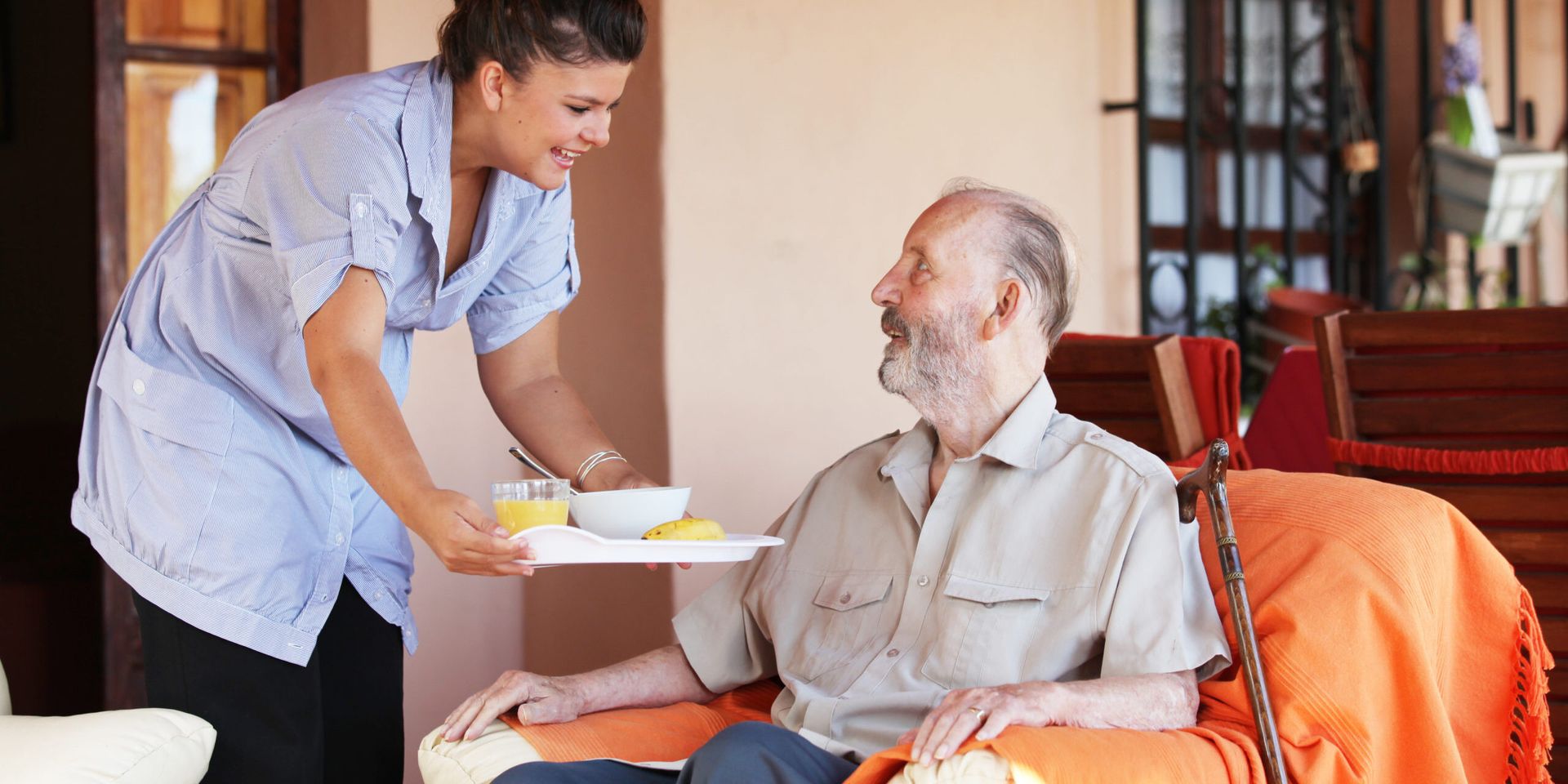 in-home care woman serving a senior lunch in a recliner