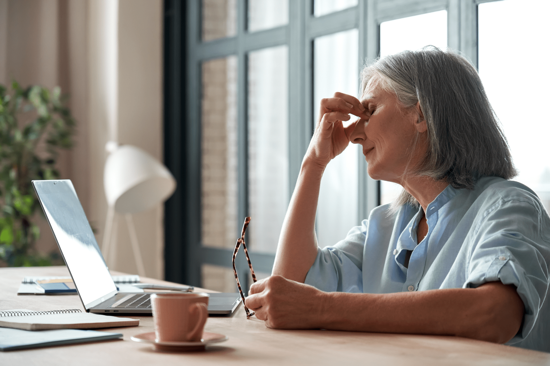 an old woman stressed at a table lookinging at a laptop