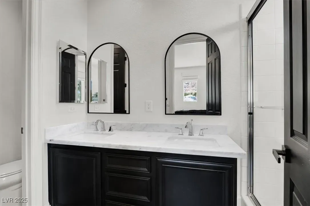 Modern bathroom vanity with two mirrors, white countertop, and black cabinets