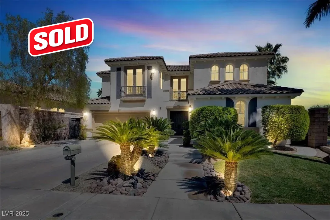 Sold sign on a lit two-story house at dusk with a landscaped front yard